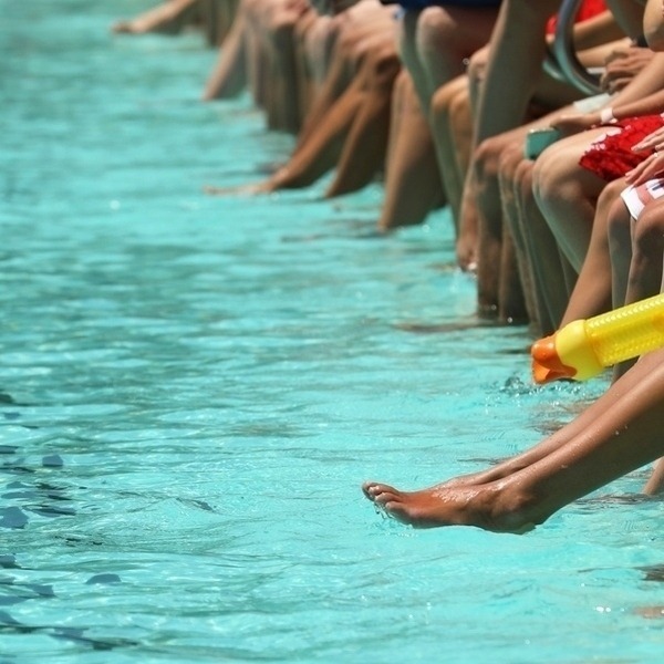 A Bright Aqua Blue Swimming Pool With Students Sitting, Dangling